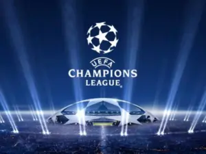 Logo da UEFA Champions League sobre fundo azul, com holofotes simulando luzes de estádio e uma representação estilizada de uma arena iluminada no centro.