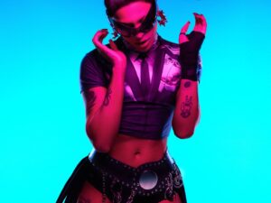 Pabllo Vittar dançando com cabelo preso e óculos, vestido top e shorts