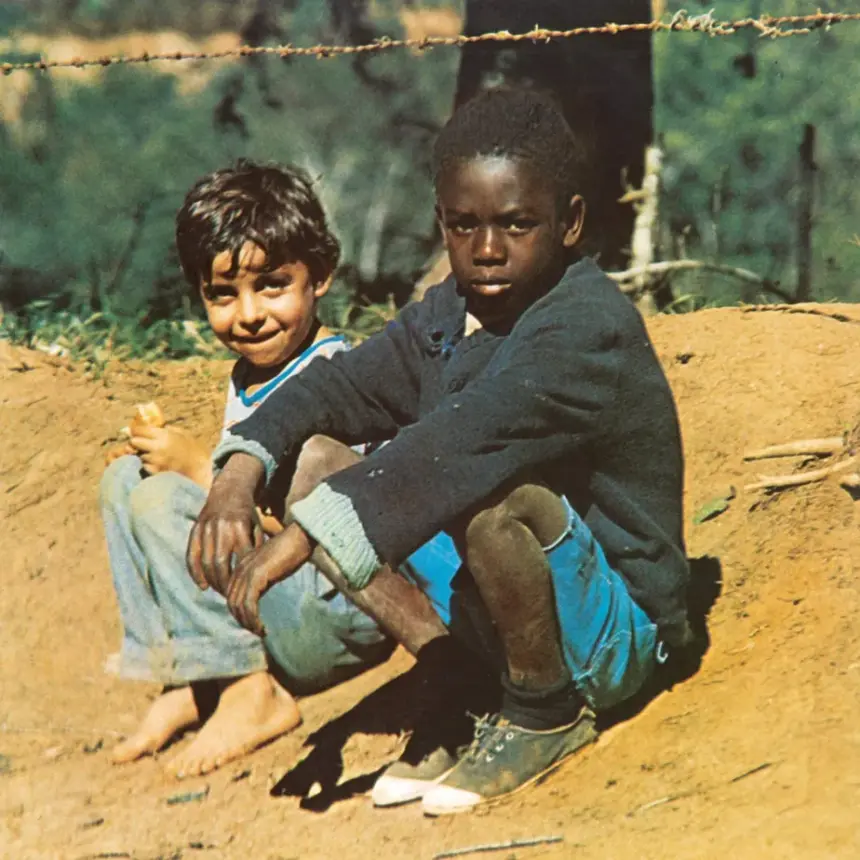 Dois meninos sentados em estrada de terra, um branco e outro negro, ao lado de uma cerca de arame farpado; imagem da capa do álbum "Clube da Esquina" de 1972.