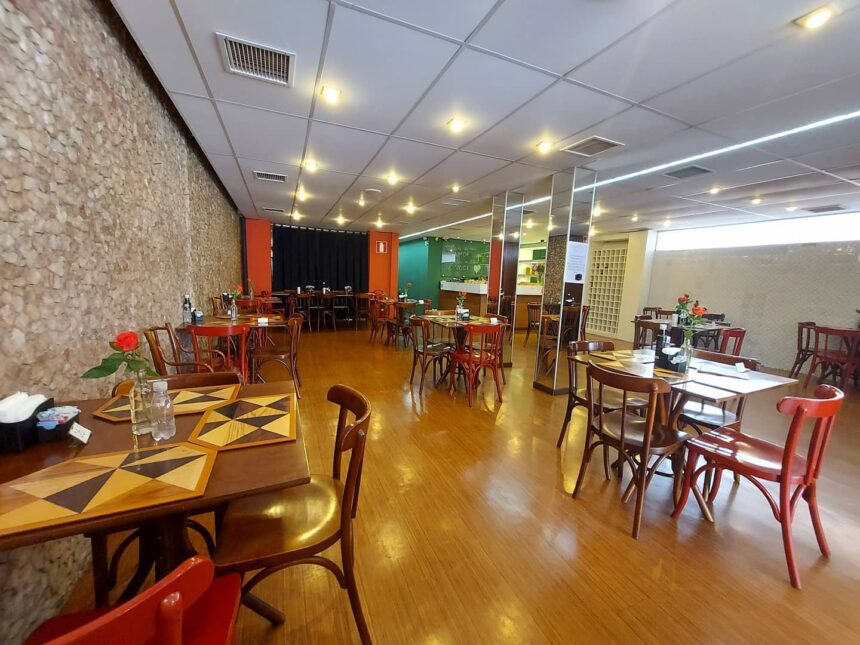Imagem mostra interior de restaurante com mesas e comidas prontas.