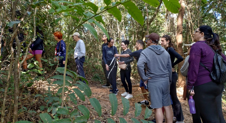 Imagem mostra pessoas de diferentes idades fazendo trilha juntas.