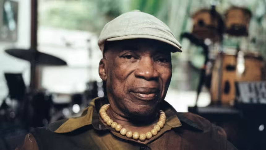 Cantor usa chapéu e colar, transmitindo serenidade e carisma, em uma imagem que reflete sua importância para a música brasileira.