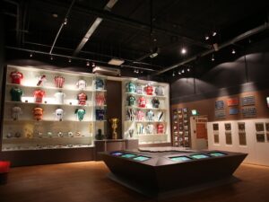 Sala expositiva do Museu Brasileiro do Futebol no Mineirão com camisas históricas de clubes, troféus e mesas interativas ao centro.