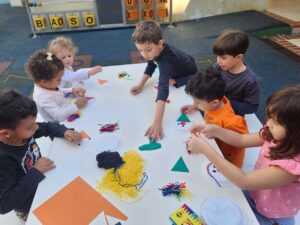 Crianças sentadas ao redor de uma mesa brincando.