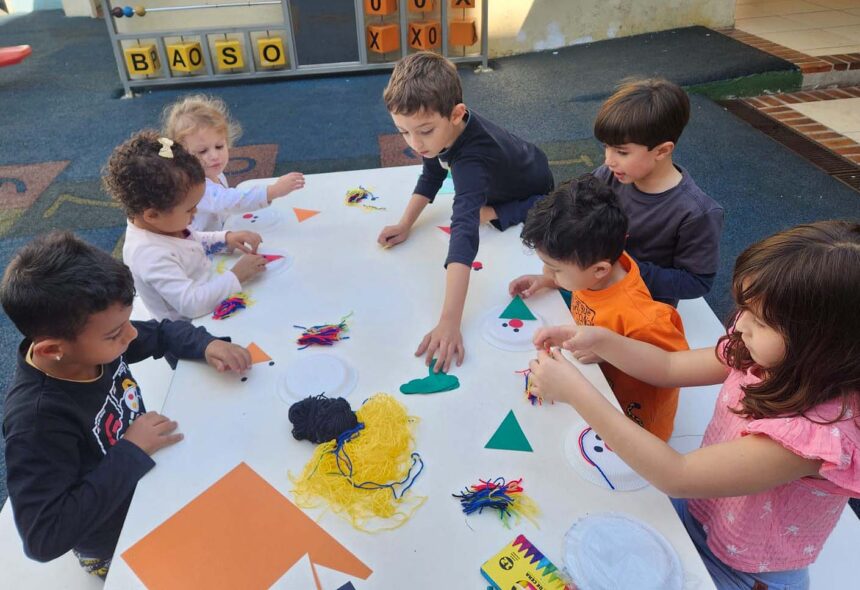 Crianças sentadas ao redor de uma mesa brincando.