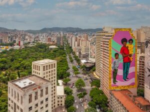 Vista aérea de Belo Horizonte com parque, avenida e edifícios, incluindo murais coloridos de pessoas.