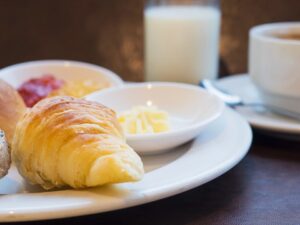 Croissant, pão, geleias, manteiga, leite e café em uma mesa de café da manhã