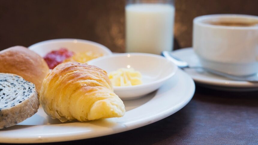 Croissant, pão, geleias, manteiga, leite e café em uma mesa de café da manhã