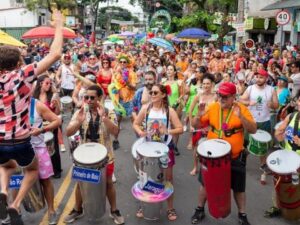 Multidão celebrando o Carnaval com bateria de percussão em rua de Belo Horizonte.