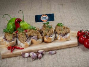 Cinco torradinhas com carne e molho, pimentas, tomate, alho e bandeira Comida Di Buteco.