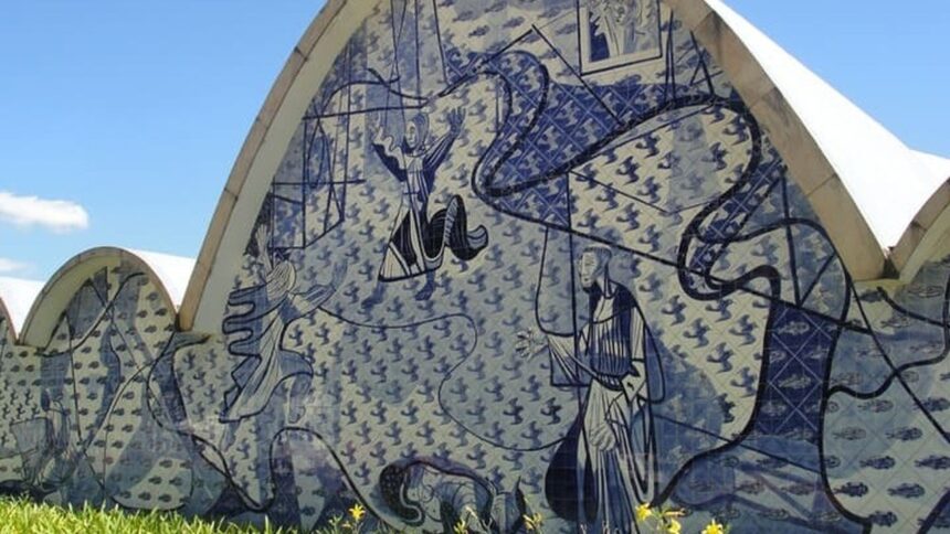 Parede de azulejos azuis e brancos da Igreja da Pampulha com figuras e céu azul.