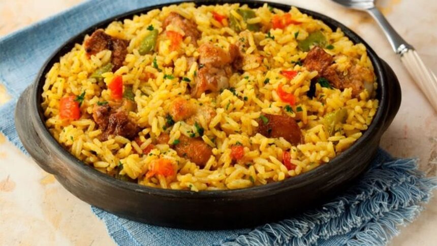 Galinhada caseira com arroz amarelo, frango, pimentões vermelho e verde em panela de barro.