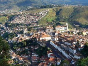 Vista panorâmica de uma cidade colonial com telhados de barro e igrejas brancas em um vale.