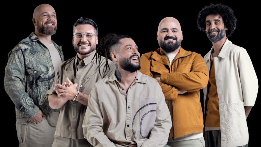 Cinco homens sorrindo, com barbas e cabelo, em fundo preto.