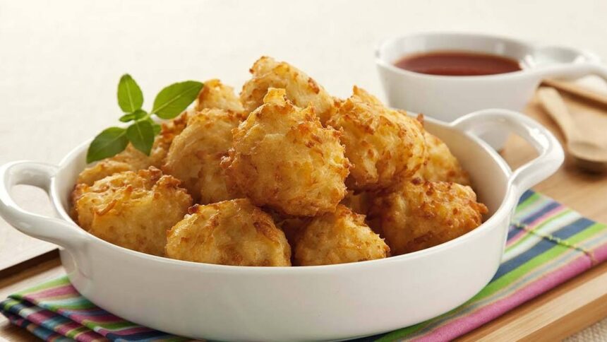 Bolinhos de arroz fritos e dourados em uma tigela branca, guarnecidos com manjericão.