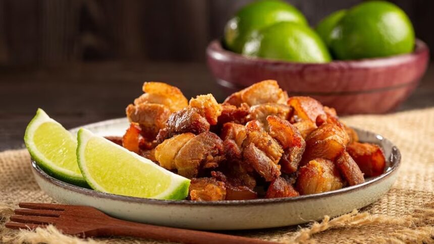 Torresmo frito crocante em prato com fatias de limão e limões frescos no fundo.