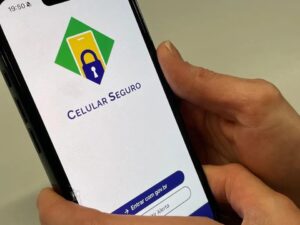 Mãos seguram smartphone com aplicativo Celular Seguro, exibindo logo e botão 'Entrar com gov.br'.