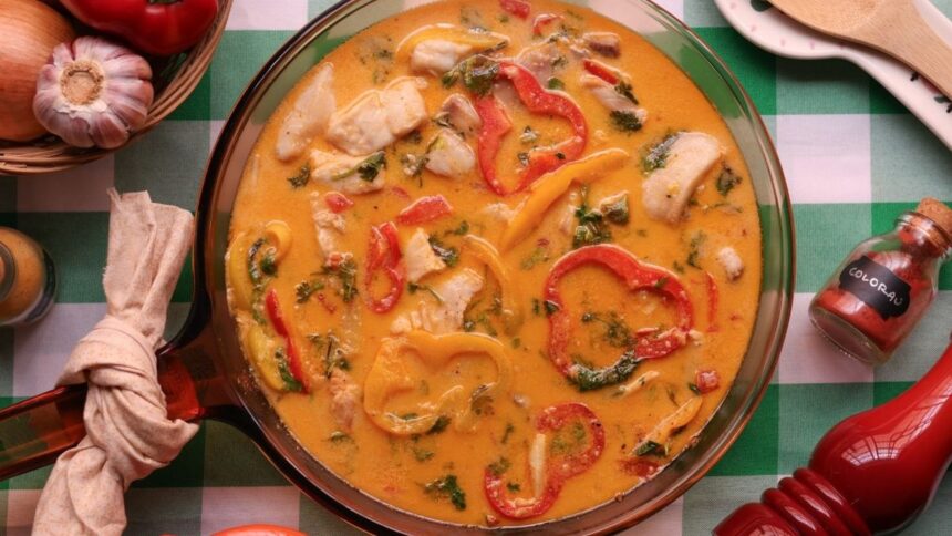 Ensopado de peixe, pimentões, coentro, molho em travessa de vidro. Tempero colorau.
