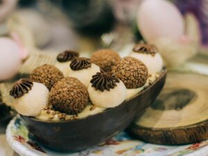 Ovo de Páscoa de chocolate meio a meio, recheado com creme claro e brigadeiros variados em um prato.