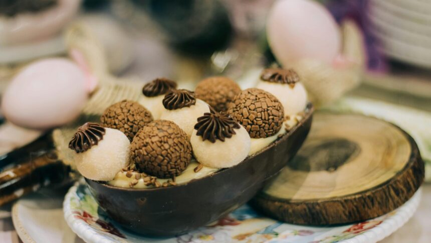 Ovo de Páscoa de chocolate meio a meio, recheado com creme claro e brigadeiros variados em um prato.