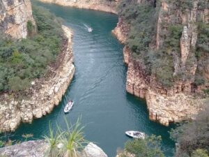 Vista aérea de cânions rochosos com rio verde-azulado e lanchas cheias de turistas.