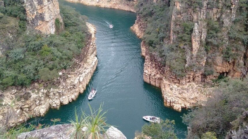 Vista aérea de cânions rochosos com rio verde-azulado e lanchas cheias de turistas.