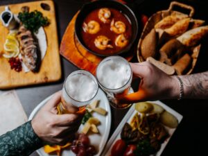Mesa de restaurante com pratos variados e um brinde entre amigos