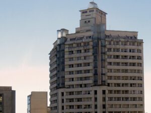Edifício Acaiaca, prédio alto de arquitetura Art Déco em Belo Horizonte, com topo de vidro, contra céu azul.