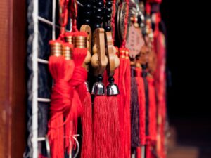 Borlas vermelhas, contas pretas e ornamentos de madeira esculpida, representando a cultura chinesa.