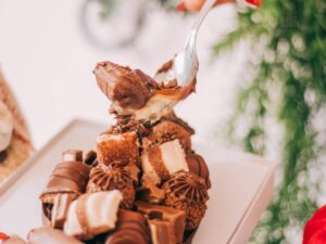 Mão com colher tirando recheio cremoso de ovo de Páscoa com chocolates e bombons.