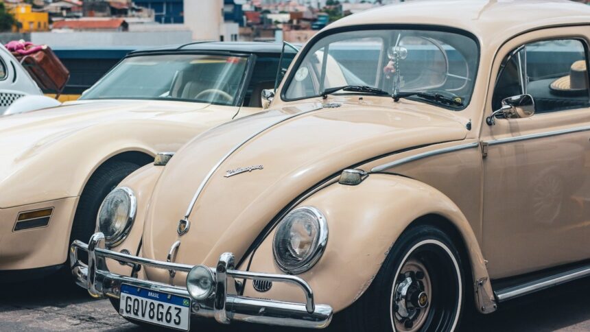 Volkswagen Fusca bege e Corvette creme antigos expostos em evento automotivo.