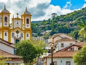 Cidade histórica de Ouro Preto com igreja colonial e casas em encosta verde.