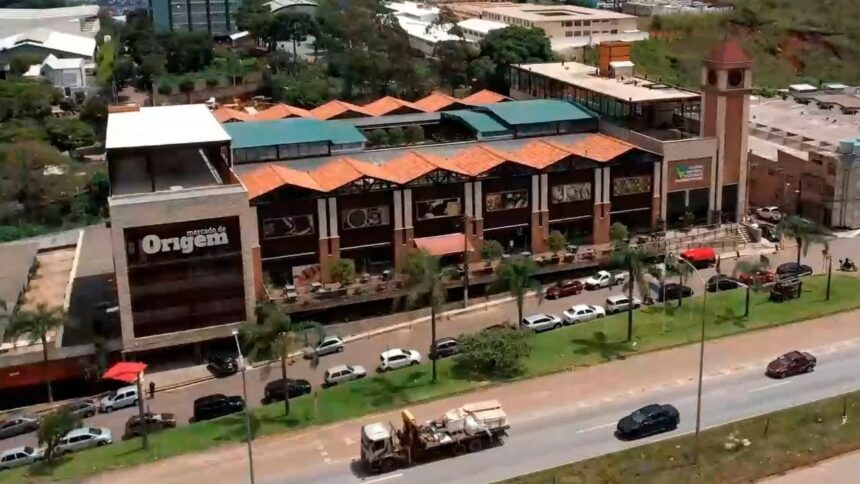 Vista aérea do Mercado de Origem com edifícios, torre do relógio, sinalização e rua movimentada.