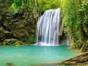 Cachoeira em floresta tropical caindo em lagoa verde cercada por rochas musgosas