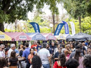 Multidão em feira ao ar livre com barracas APROXIMA e banners das cervejarias Krug Bier e Pedrosa.