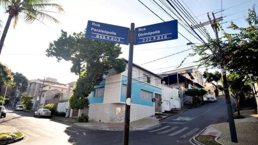 Sinal de rua azul com 'Rua Paraisópolis' e 'Rua Divinópolis', em esquina arborizada de BH.