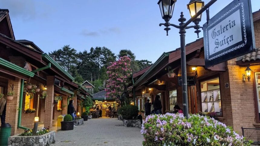 Rua iluminada com lojas de tijolos, letreiro 'Galeria Suíça', flores e pessoas.