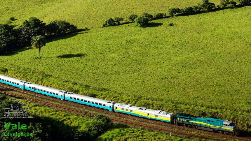 Trem de passageiros longo em trilhos através de paisagem verde e montanhosa, com logotipo Vale.