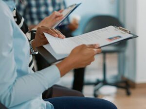 Candidata sentada na fila e recebendo arquivos de cv, esperando para iniciar entrevista de emprego sobre oportunidade de carreira. Mulher se preparando para participar de reunião de recrutamento com funcionário de RH.