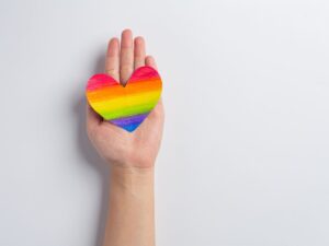 As mãos da mulher seguram o coração do arco-íris para o conceito de orgulho da comunidade LGBT