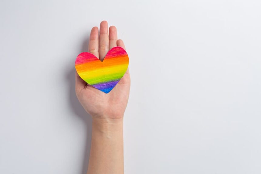 As mãos da mulher seguram o coração do arco-íris para o conceito de orgulho da comunidade LGBT