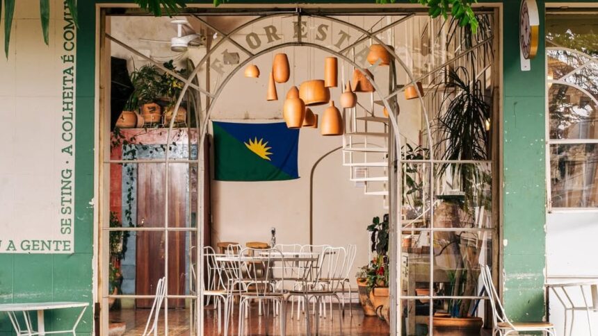 Entrada do restaurante Florestal com mesas brancas, vasos suspensos e bandeira de Pernambuco.