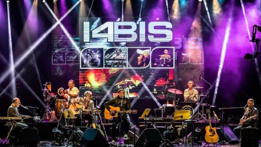 Banda 14 Bis no palco. Músicos com guitarras, teclado, bateria. Telão exibe '14 BIS'.