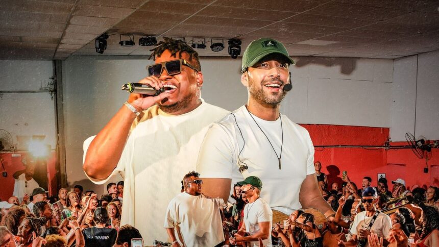 Dois cantores em palco, um com microfone, outro com boné, diante de público animado.