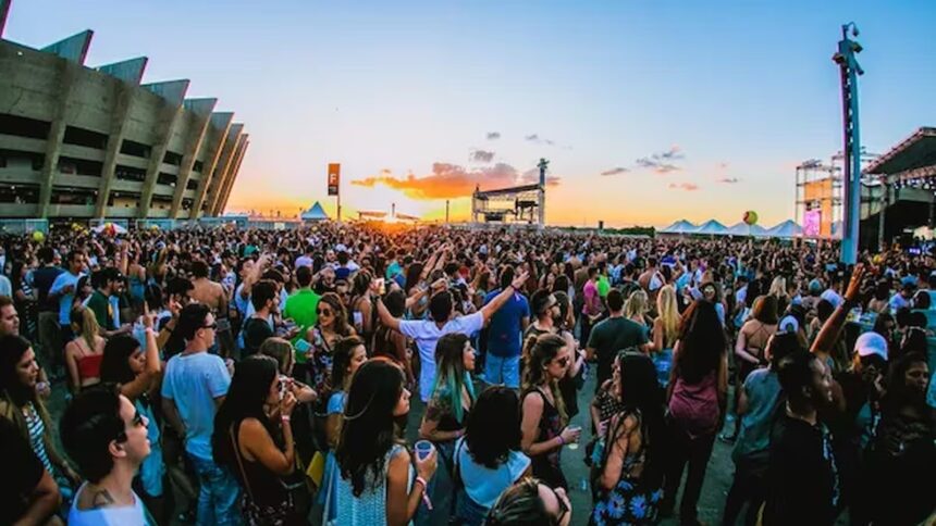 Grande multidão em festival de música ao pôr do sol com estádio e palco