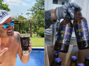 Homem sorridente com boné e óculos de sol. Mãos enluvadas seguram garrafas de cerveja Läut Meidia com rótulo azul.