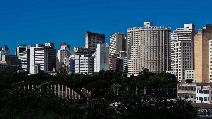 Skyline urbano com edifícios altos, céu azul, árvores e uma ponte em Belo Horizonte