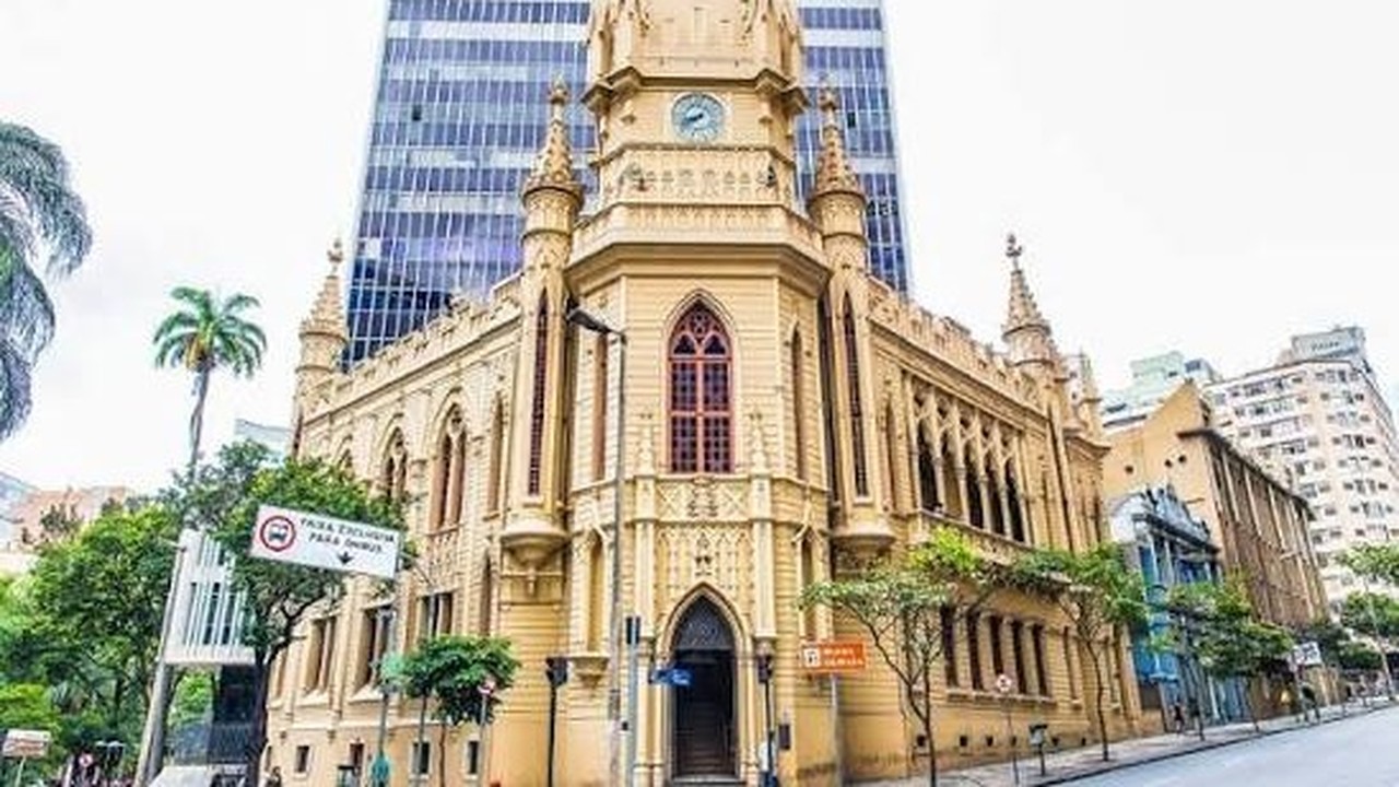 Edifício histórico do Museu de Artes e Ofícios em BH com torre do relógio e arranha-céu.