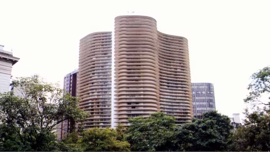 Vista do Edifício Niemeyer, na Praça da Liberdade, em Belo Horizonte, com sua fachada de curvas marcantes e árvores em primeiro plano