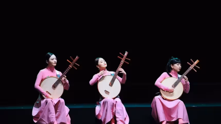 três mulheres da Orquestra chinesa tocando em palco